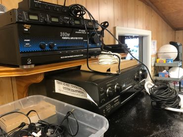 Audio equipment and cables arranged on a black table in a wooden room.