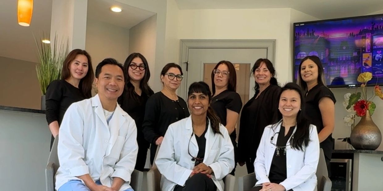 Medical team posing indoors, some in white coats, others in black uniforms.