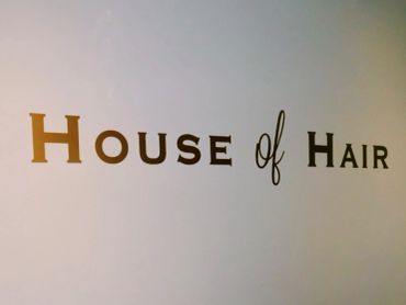 Sign reading 'House of Hair' on a wall.