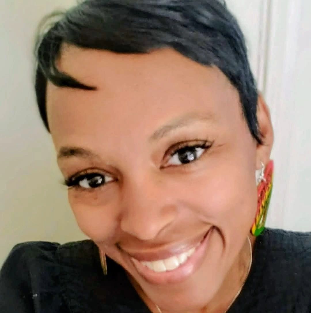Close-up of a smiling woman with short hair and colorful earrings.