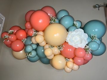 Colorful balloon garland with a white rose and small flowers.