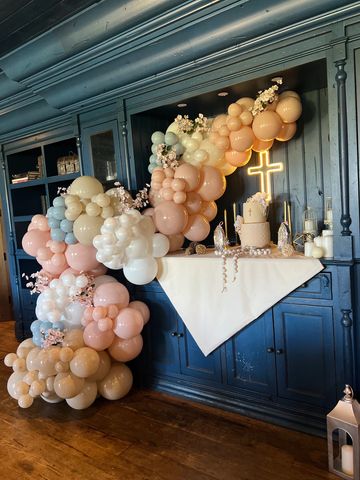Balloon arch decoration around a lit cross with a cake.