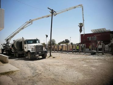 Concrete mixer truck with extended boom pump at a construction site.
