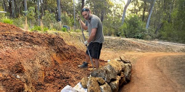 Tom Jensen building a rock retaining wall beside a gravel driveway near Batemans Bay