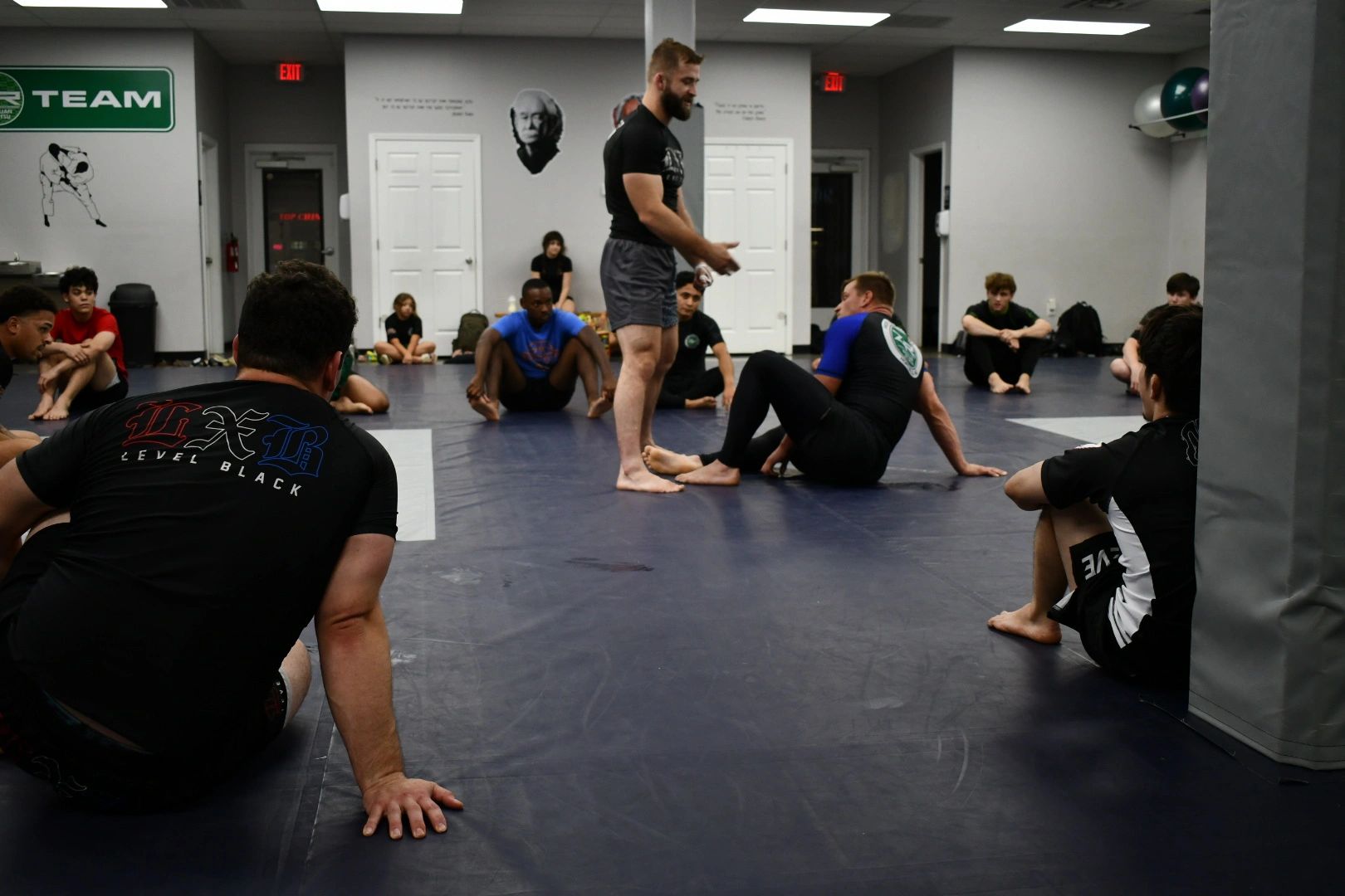 A Brazilian Jiu Jitsu black belt demonstrating technique to Adults BJJ class.