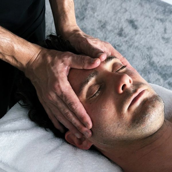 Man receiving a relaxing head massage with closed eyes.