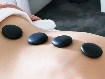 Four black hot stones placed on a person's back during a spa treatment.