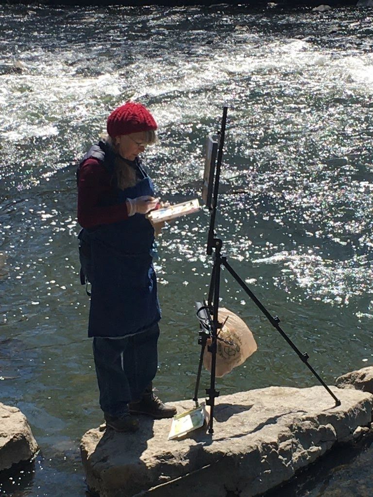 An artist standing on a rock in the middle of the river.