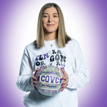 Woman holding a decorated volleyball with 'COVC' on it.