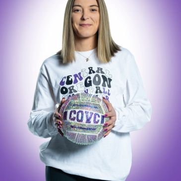 Woman holding a decorated volleyball with 'COVC' on it.