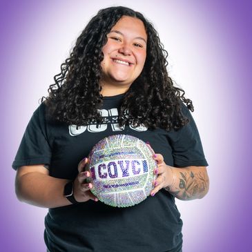 Woman smiling while holding a sparkling volleyball with COYC text.