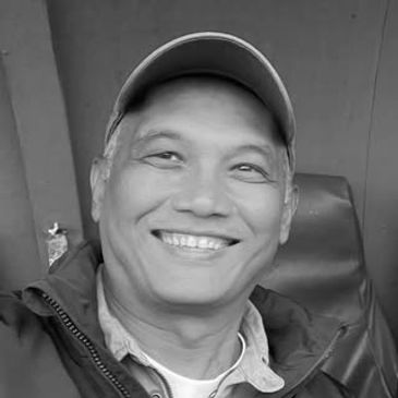 Smiling man wearing a cap in a black-and-white photo.