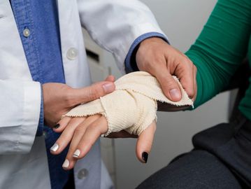 Doctor wrapping a patient's injured hand with a bandage.