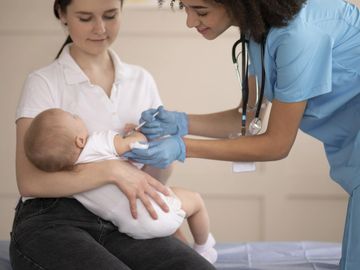 A nurse gives a baby a vaccination while the mother holds the child.