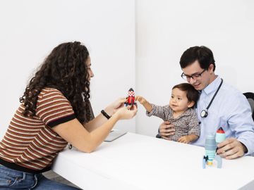 A doctor with a child and a woman playing with toy rockets.