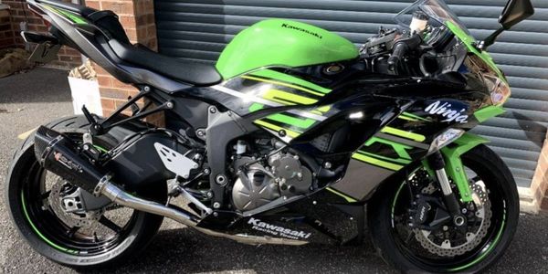 Green and black Kawasaki Ninja sport motorcycle parked outside after security upgrade.