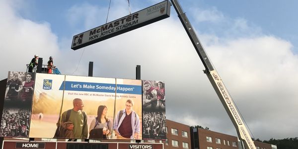 Sign being hoisted in Hamilton, Ontario by boom truck rental for steel erecting company