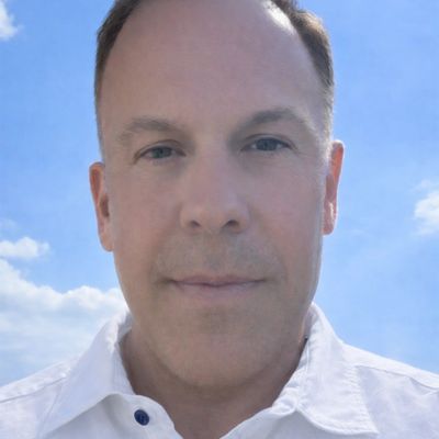 Portrait of a man in a white shirt against a blue sky.