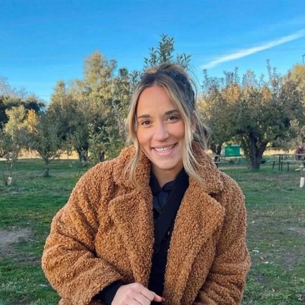 Smiling woman in a cozy brown coat outdoors.