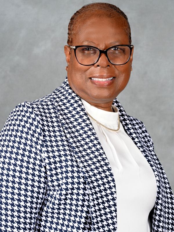 Smiling woman in glasses and a houndstooth blazer.