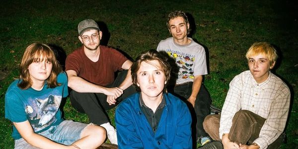 A group of five young adults sitting on grass at night.