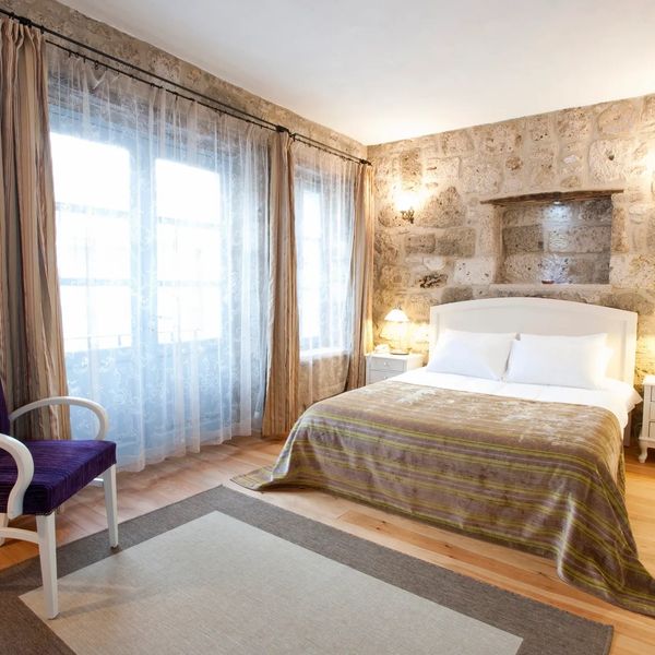 Cozy bedroom with stone walls, a large bed, and a purple armchair.