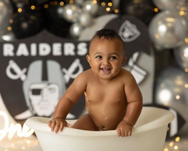 raider cake smash little boy smiling in tub during his cake smash session at inland empire studio.