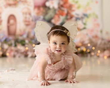 fairy first birthday cake smash session of big blue eyed baby during her cake smash session,
