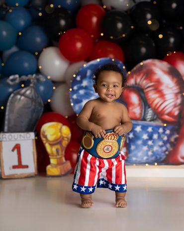 boxing cake smash session, little boy in boxing outfit wearing belt during his studio cake smash,