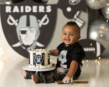 smiling little boy theme Raiders cake smash session and raiders jersey at studio in Corona, Ca,