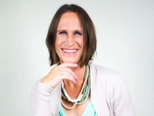 Smiling woman with layered beaded necklaces and casual attire.