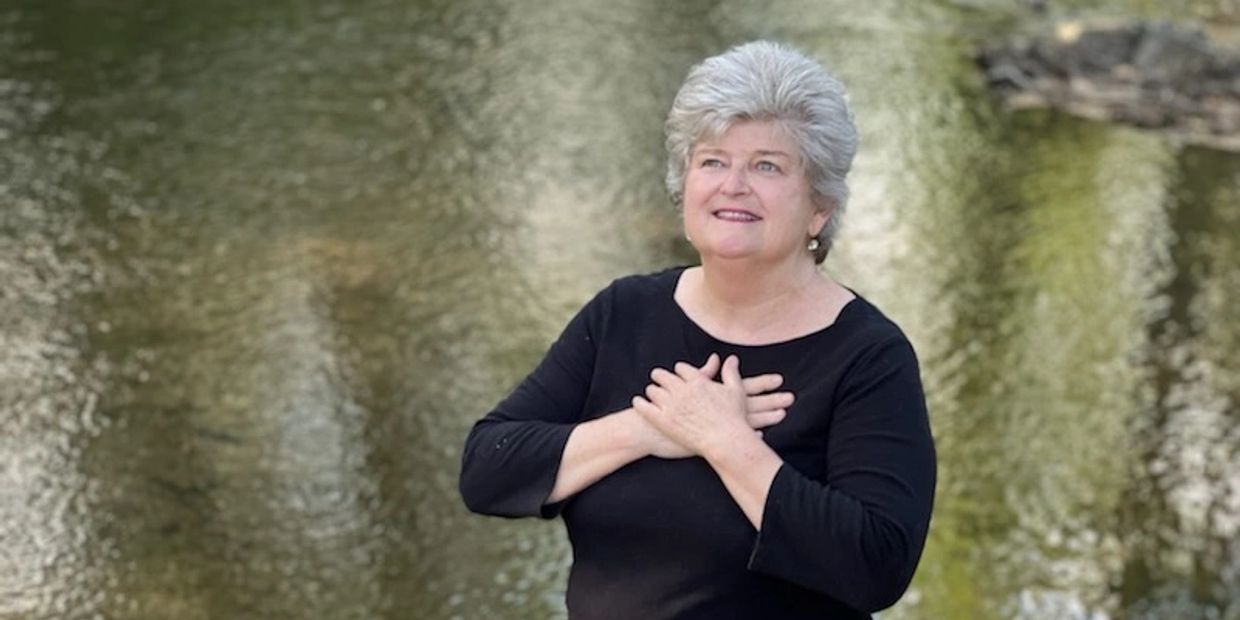 Reverend Charlotte Mcginnis smiling with her hands over her hart.