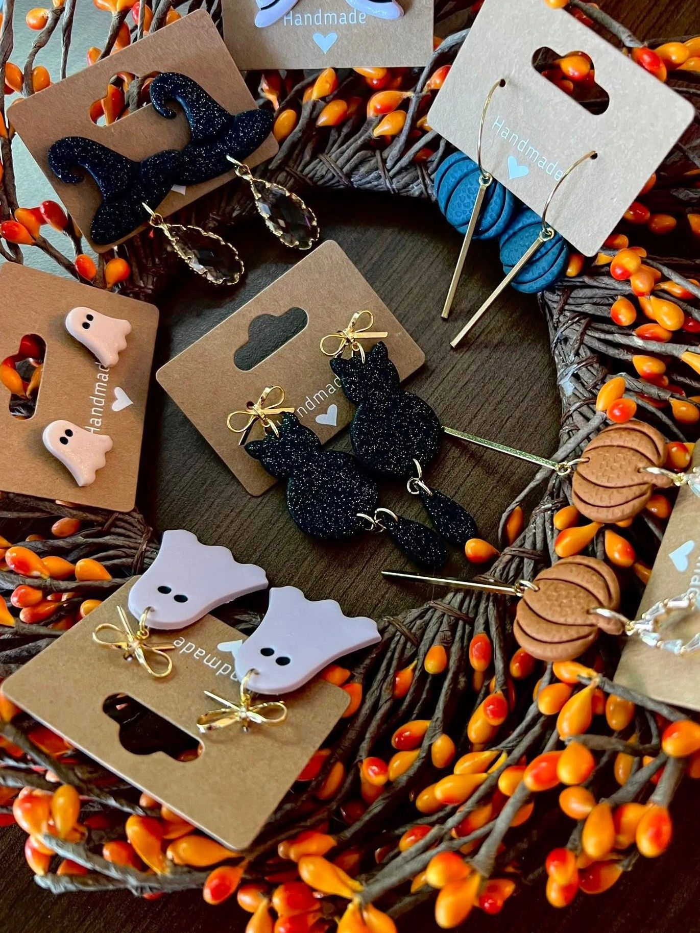 Handmade Halloween-themed earrings on display with autumn decor.