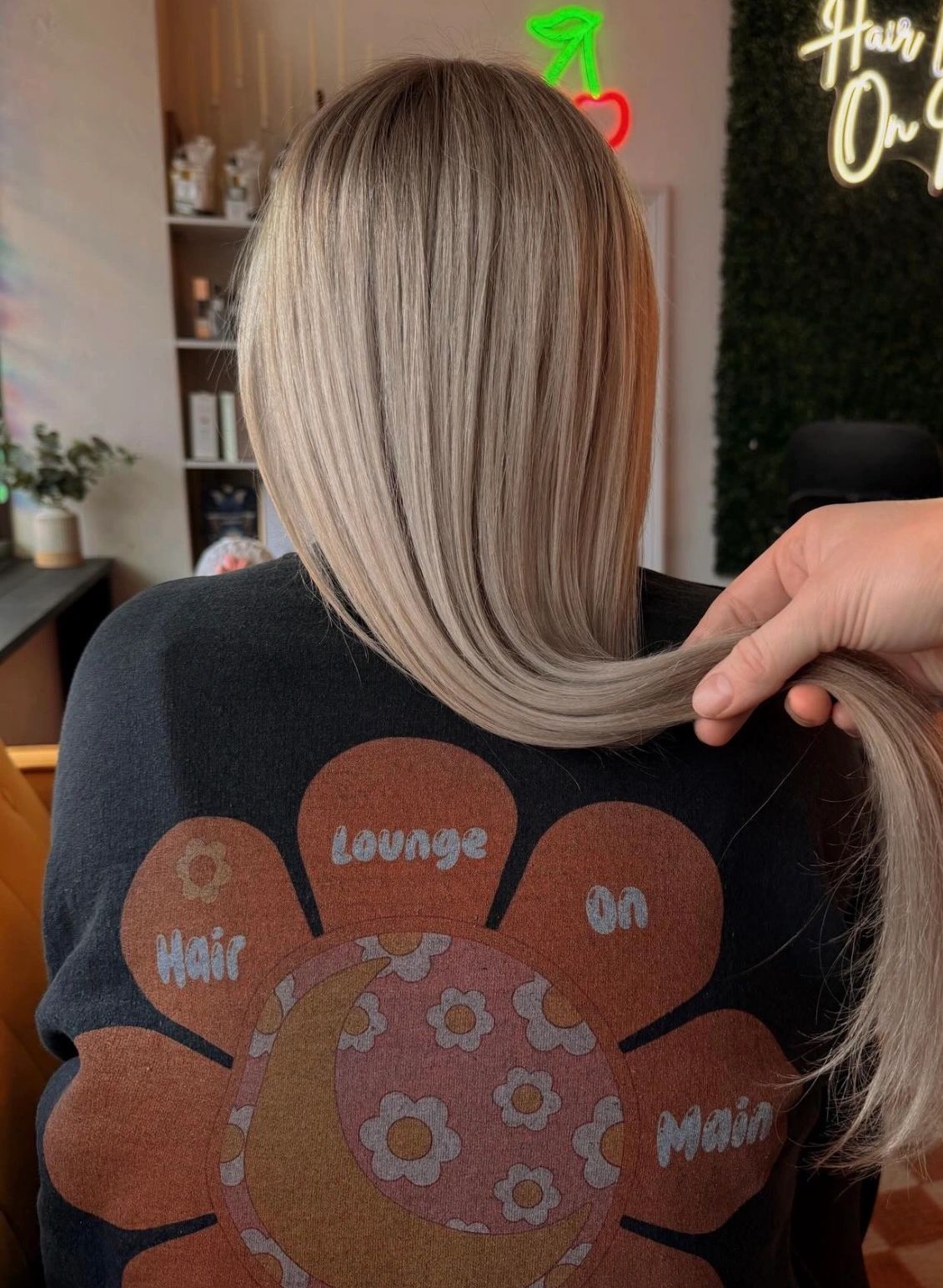 Person with smooth, straight blonde hair being held at the ends.