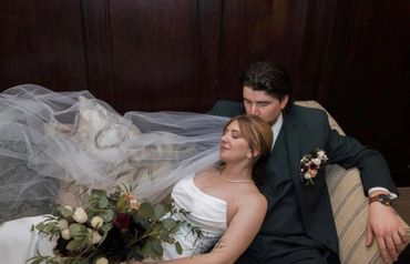 Bride and groom relaxing on a couch after their wedding ceremony.