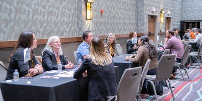 People engaged in discussions at a networking event with tables and chairs.