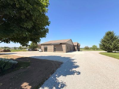 Single-story beige house with a gravel driveway on a sunny day.