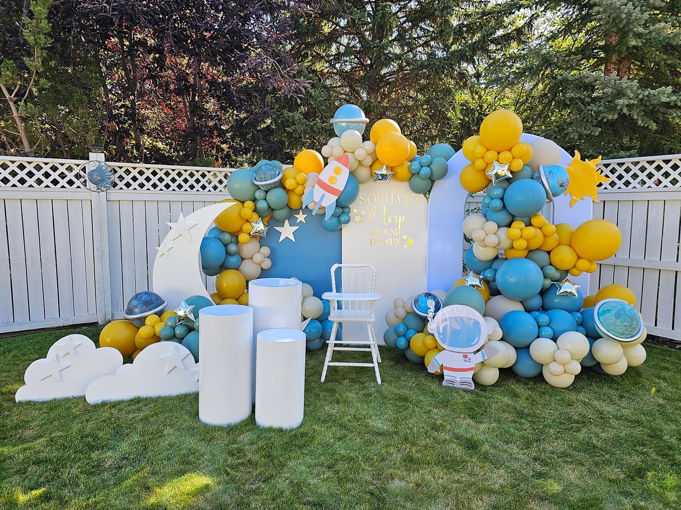 A space-themed custom birthday balloon arrangement with rockets and astronauts on a lawn.