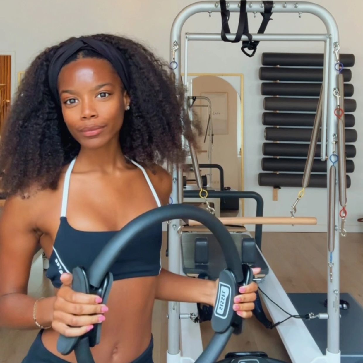 Woman in sportswear holding a fitness ring in a Pilates studio.