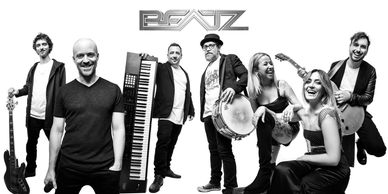 A diverse band posing with instruments in a black-and-white photo.