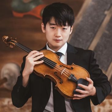 Young man holding a violin in a formal setting.