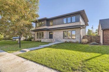 Modern two-story house with a mix of stone and dark siding.