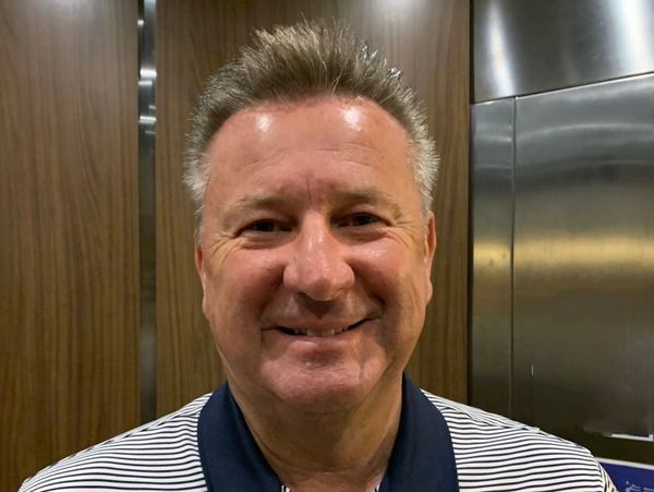 Smiling man with gray hair in a striped polo shirt.