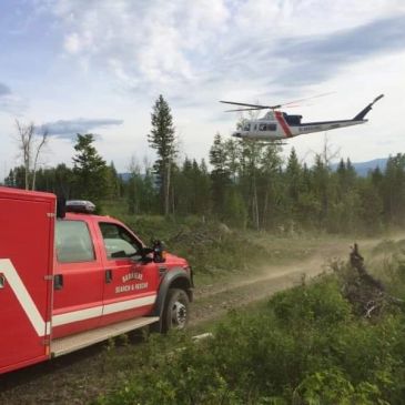Rescue vehicle and helicopter in forested area during a search and rescue mission.