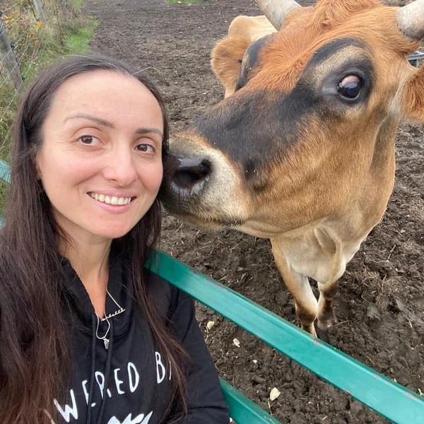 She Smiles at the Camera, Cattle Cow Beside Her.