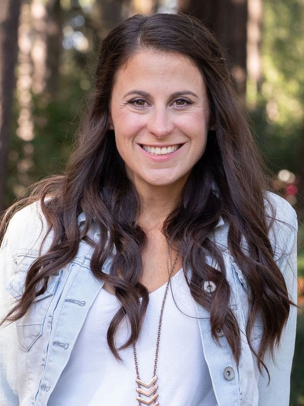 Smiling woman with long brown hair outdoors.