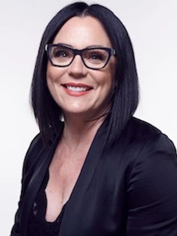 Woman with black glasses smiling.
