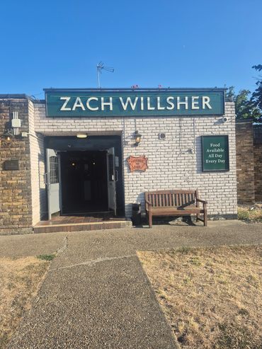 Entrance of Zach Willsher pub with a wooden bench outside.