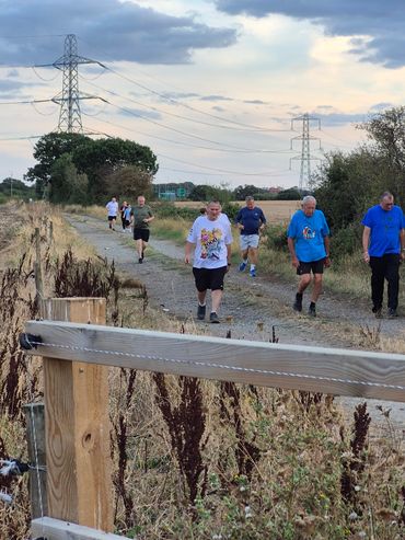 People jogging and walking on a rural path at dusk.
