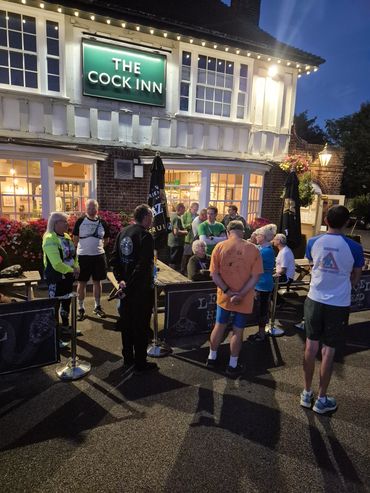 People gathered outside The Cock Inn pub at dusk.